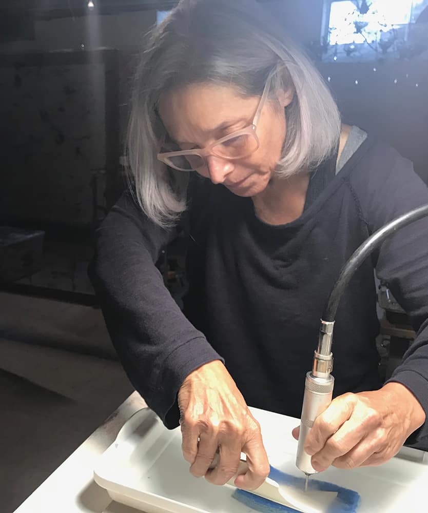 Elegant woman creating contemporary art with a steady hand, showcasing Sue E Schneider Art's studio craftsmanship.